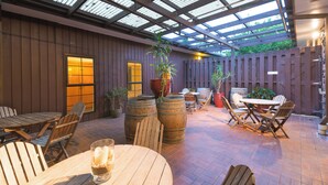 An outdoor patio with wooden tables and chairs, potted plants, and a wooden fence. - Distinction Whangarei Hotel & Conference Centre (Whangarei)