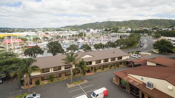 A marina with boats, a building with a brown roof, and a parking lot with cars and vans.