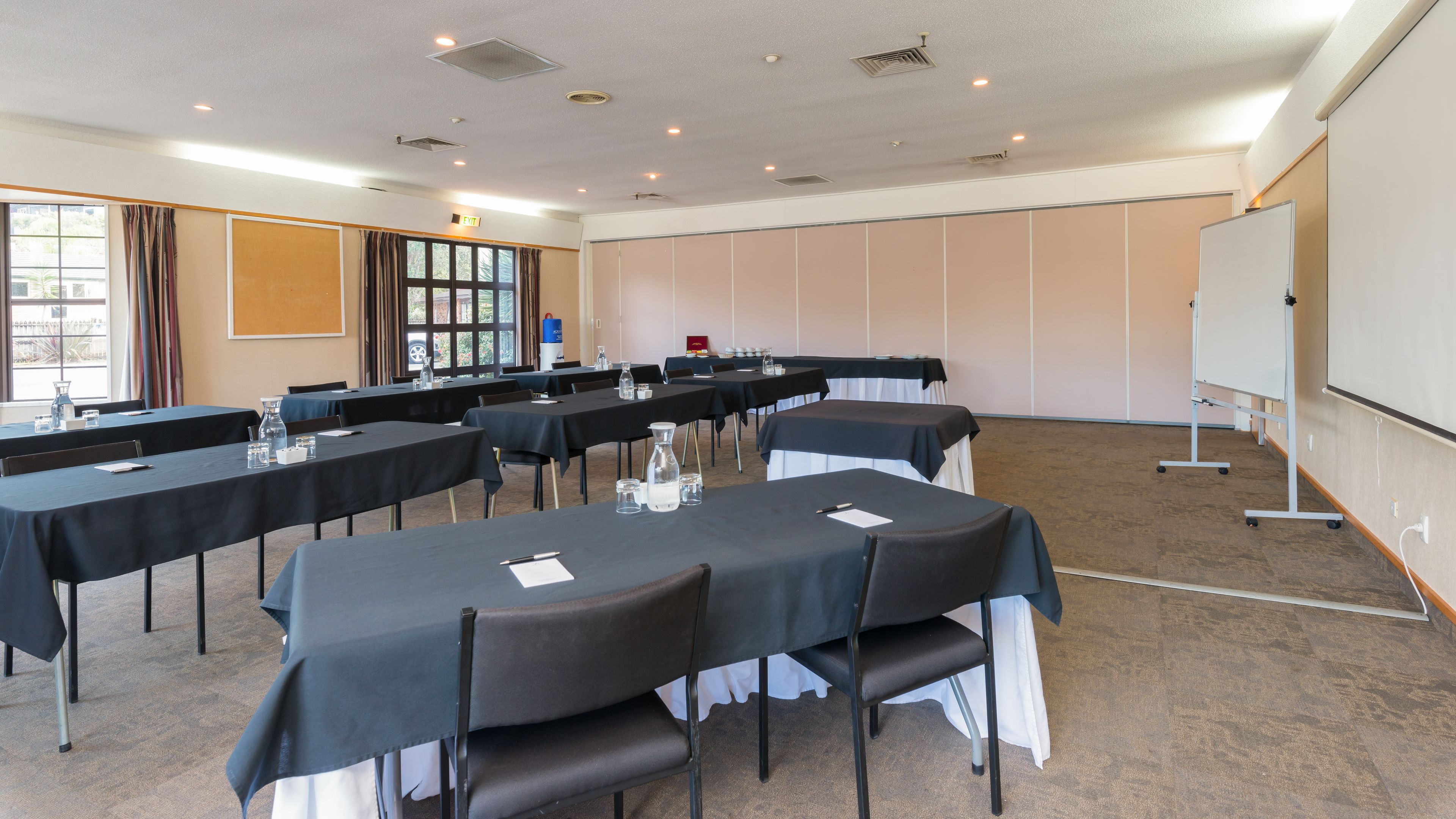 A conference room with multiple tables, chairs, and a whiteboard.