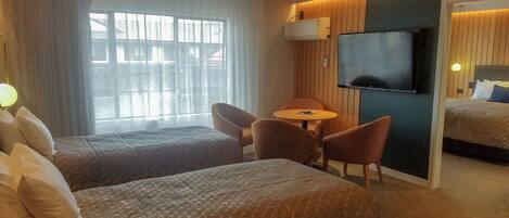 A hotel room with two beds, a TV, a small table, and a chair.