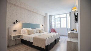 Una habitación de hotel moderna con una cama grande, mesitas de noche, un escritorio y una silla.