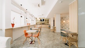 Un interior moderno con una amplia zona de comedor, mesas y sillas de madera.