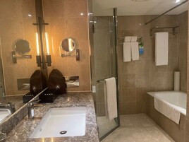 Un baño moderno con un lavabo de mármol, una cabina de ducha de vidrio y dos espejos.