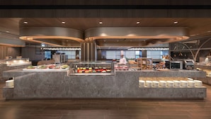 A modern breakfast buffet with a marble counter, various food options, and a chef preparing food. - Howard Plaza Hotel Kaohsiung (Kaohsiung)