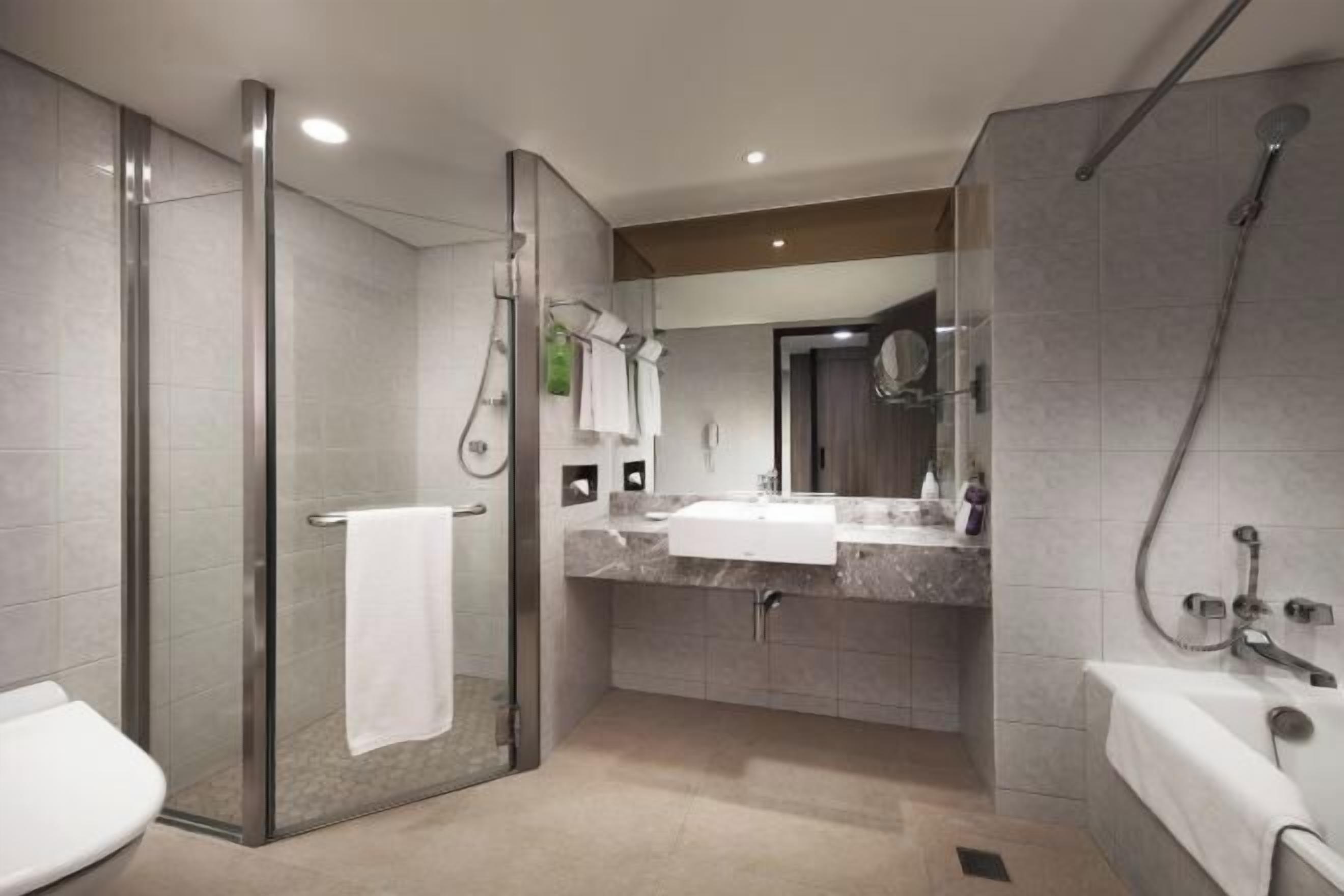 Een aparte badkuip en douche, een diep bad, een regendouche