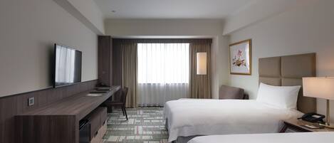 Een hotelkamer met twee bedden, een bureau, een televisie, een lamp en een raam met gordijnen.