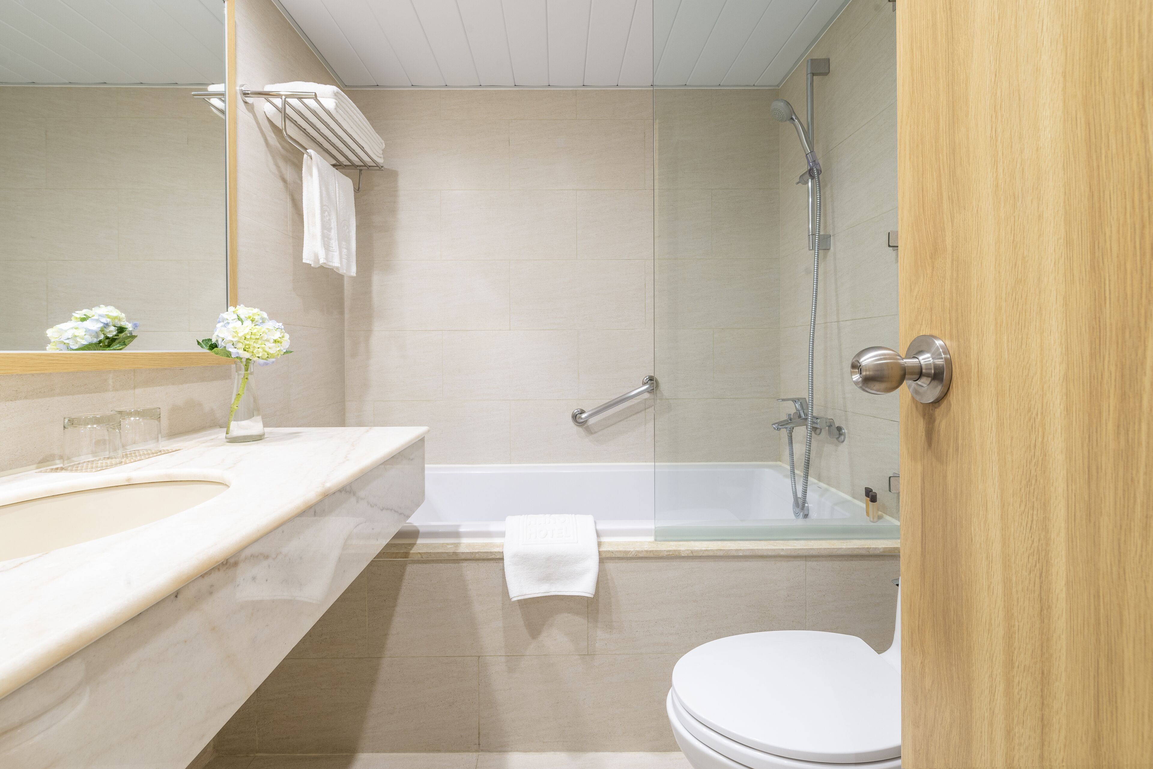 Un baño moderno con ducha de vidrio, inodoro blanco y tocador con espejo.