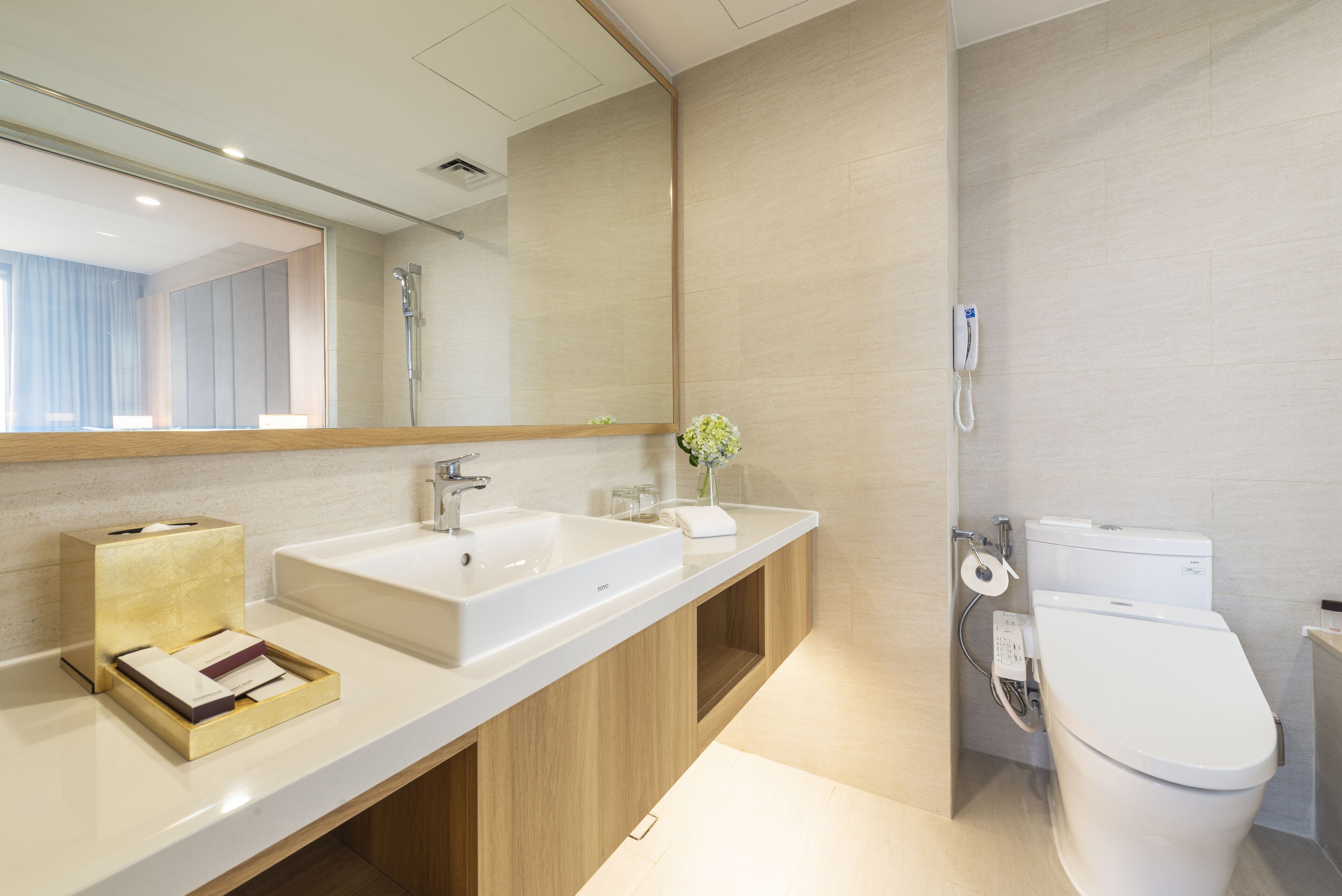 Un baño moderno con un espejo grande, dos lavamanos, un inodoro y un mueble de tocador de madera.
