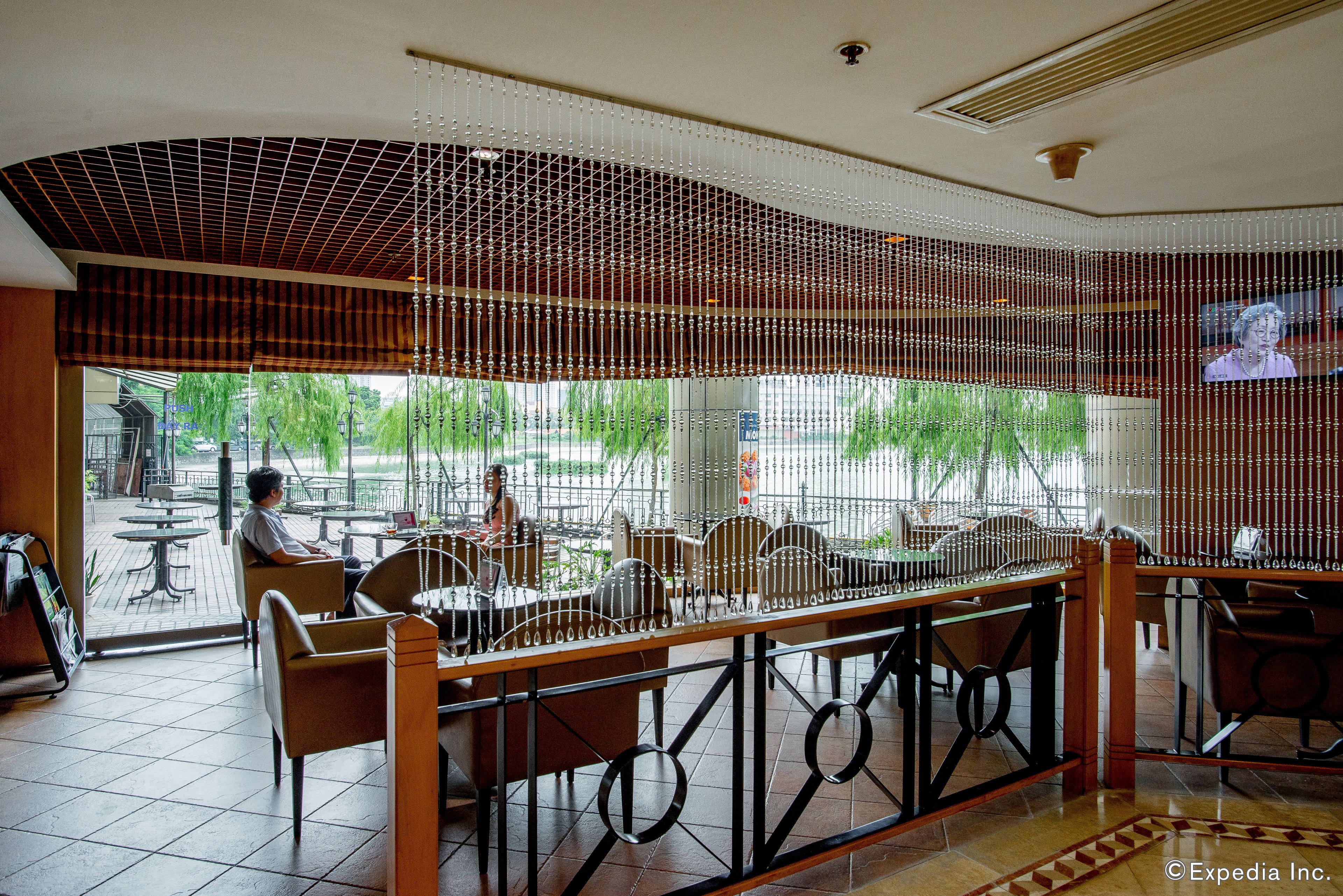 Un restaurante con vista a la calle, mesas al aire libre y un techo decorativo.