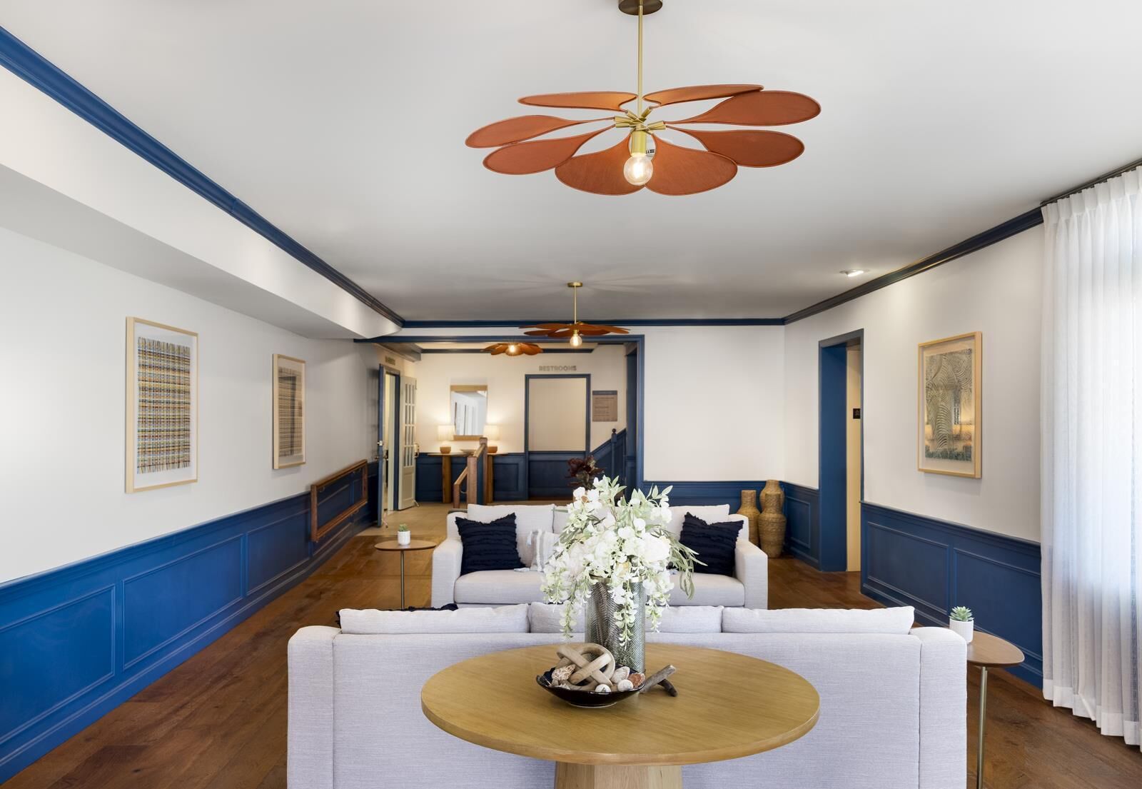 A hotel lobby with a central seating area, a ceiling fan, and framed artwork on the walls.