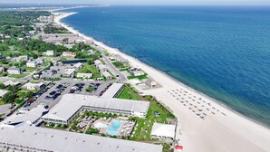 Vue aérienne d’une station balnéaire comprenant une plage, un parking et une piscine.