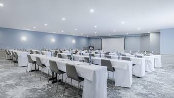 A conference room with rows of tables, chairs, and a presentation screen.