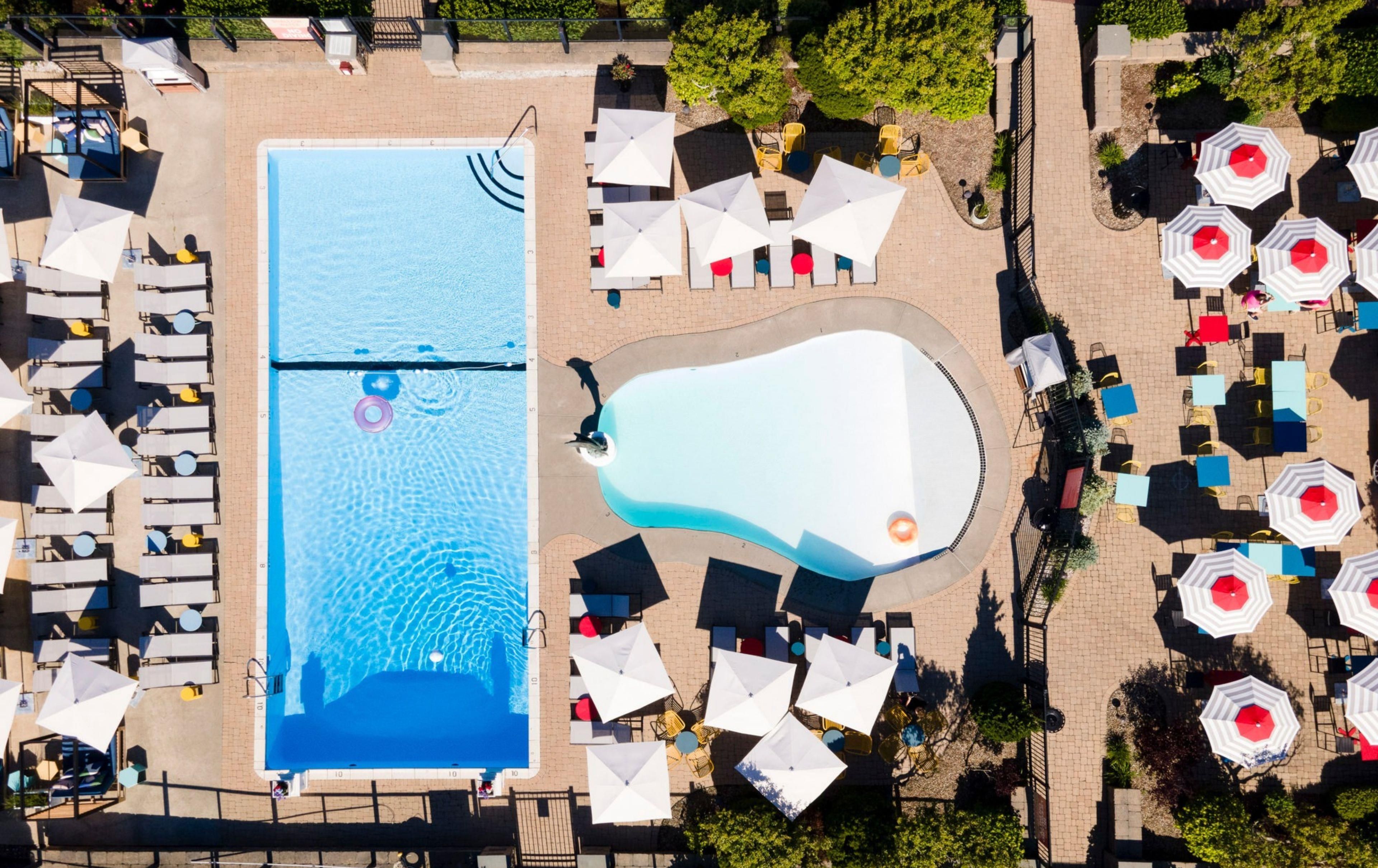 An aerial view of a swimming pool area with sun loungers and umbrellas.