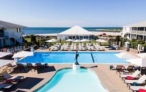 A swimming pool with lounge chairs and umbrellas, a covered area, and a view of the sea. - Red Jacket Beach Resort (South Yarmouth)