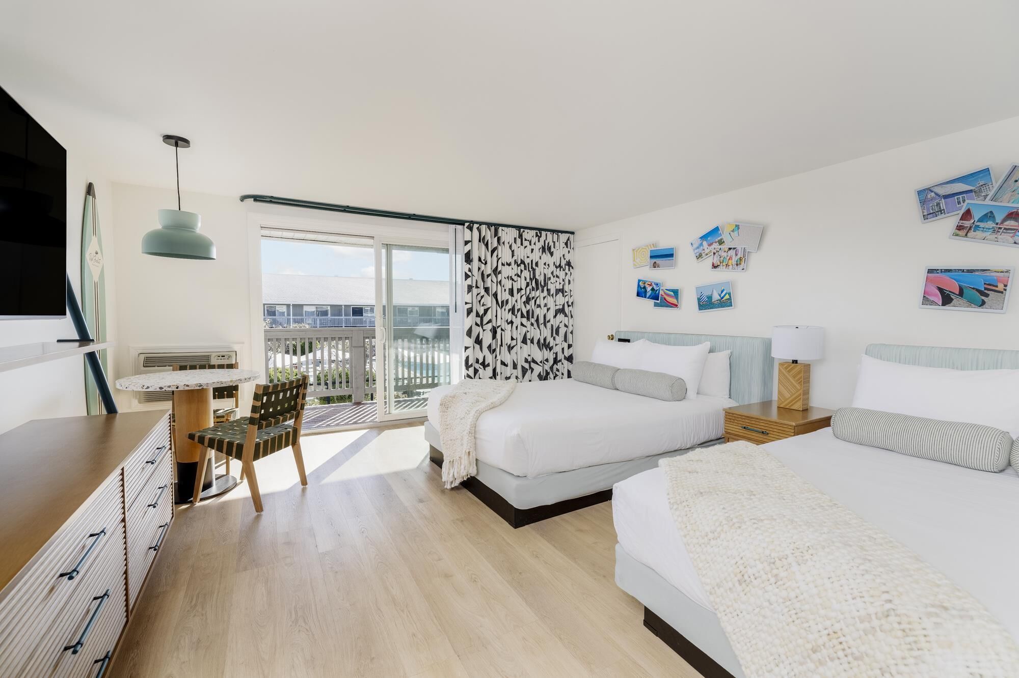 A modern hotel room with a large bed, a desk, and a balcony with a view.