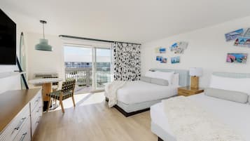 A modern hotel room with a large bed, a desk, and a balcony with a view.