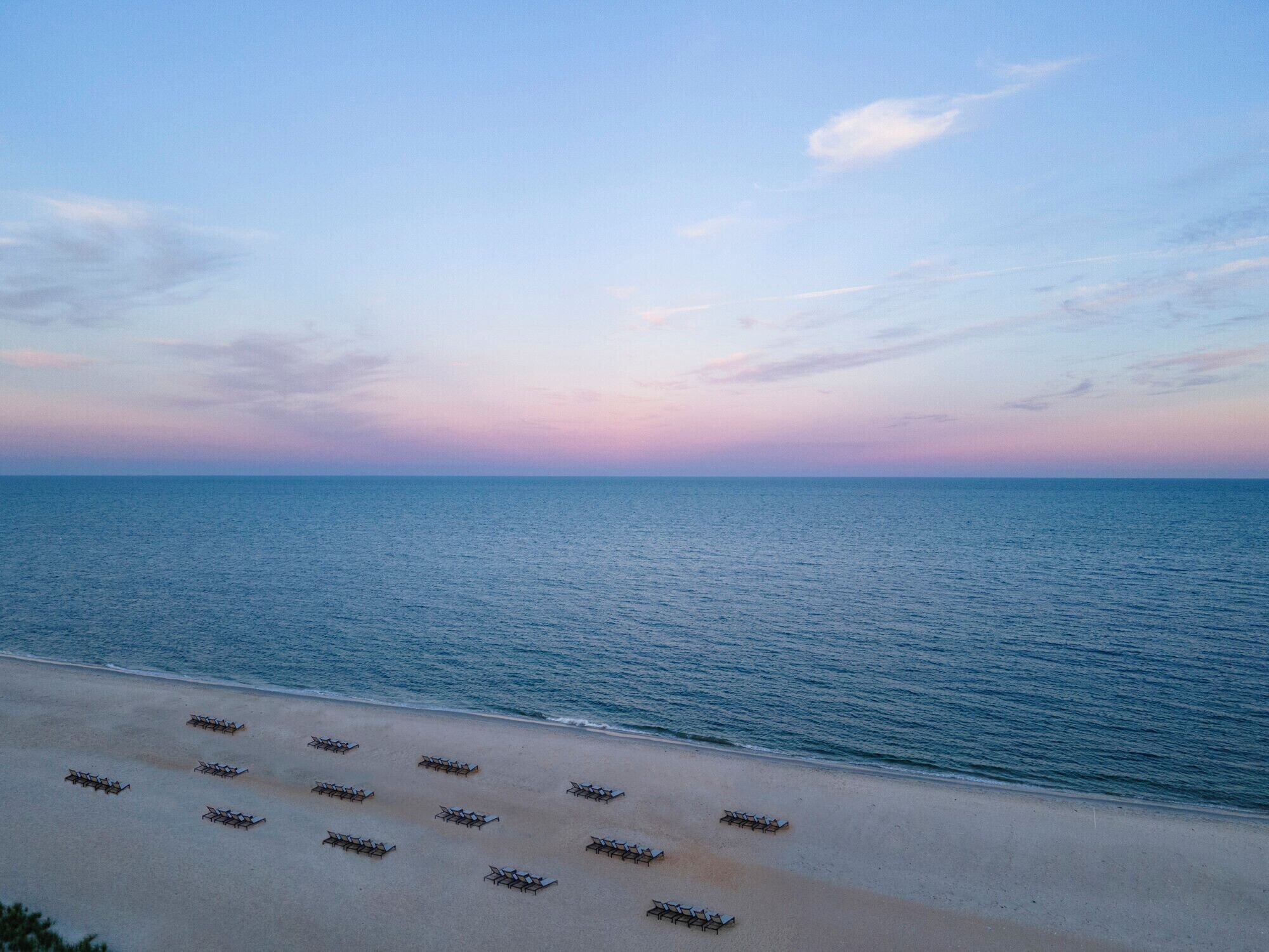 A beach with rows of sun loungers facing the sea.