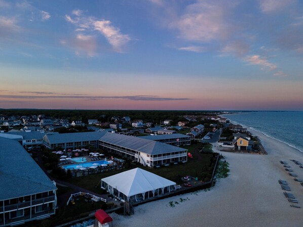 Un complejo turístico frente al mar con varias edificaciones, una playa y una zona de piscina.