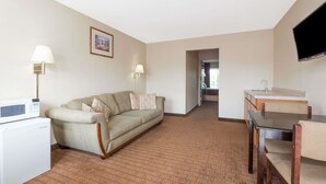 A living room with a sofa, a coffee table, a TV, and a microwave. - Howard Johnson by Wyndham Springfield (Springfield)