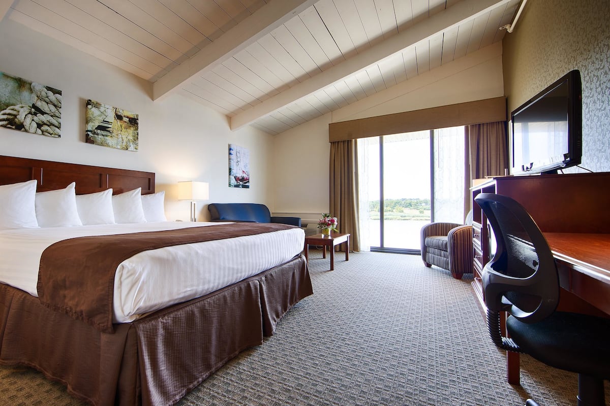 A hotel room with a large bed, a desk, a chair, and a TV.