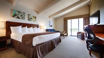 A hotel room with a large bed, a desk, a chair, and a TV.