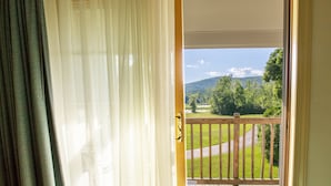 A view from a balcony with a wooden railing, a grassy landscape, and a mountain in the distance. - The Yankee Inn (Lenox)