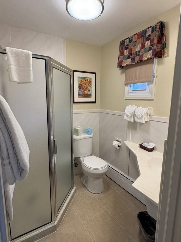 A compact bathroom with a glass shower enclosure, a toilet, and a sink area.
