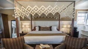 A hotel room with a four-poster bed, two armchairs, a small table with a book, and a decorative canopy. - The Yankee Inn (Lenox)
