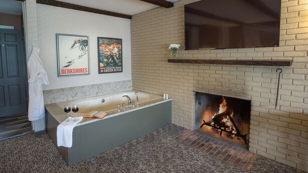 A modern bathroom with a freestanding bathtub, a fireplace, and two framed posters on the wall. - The Yankee Inn (Lenox)