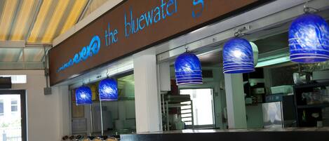 A restaurant with a bluewater grill sign, checkered counter, and blue hanging lamps.
