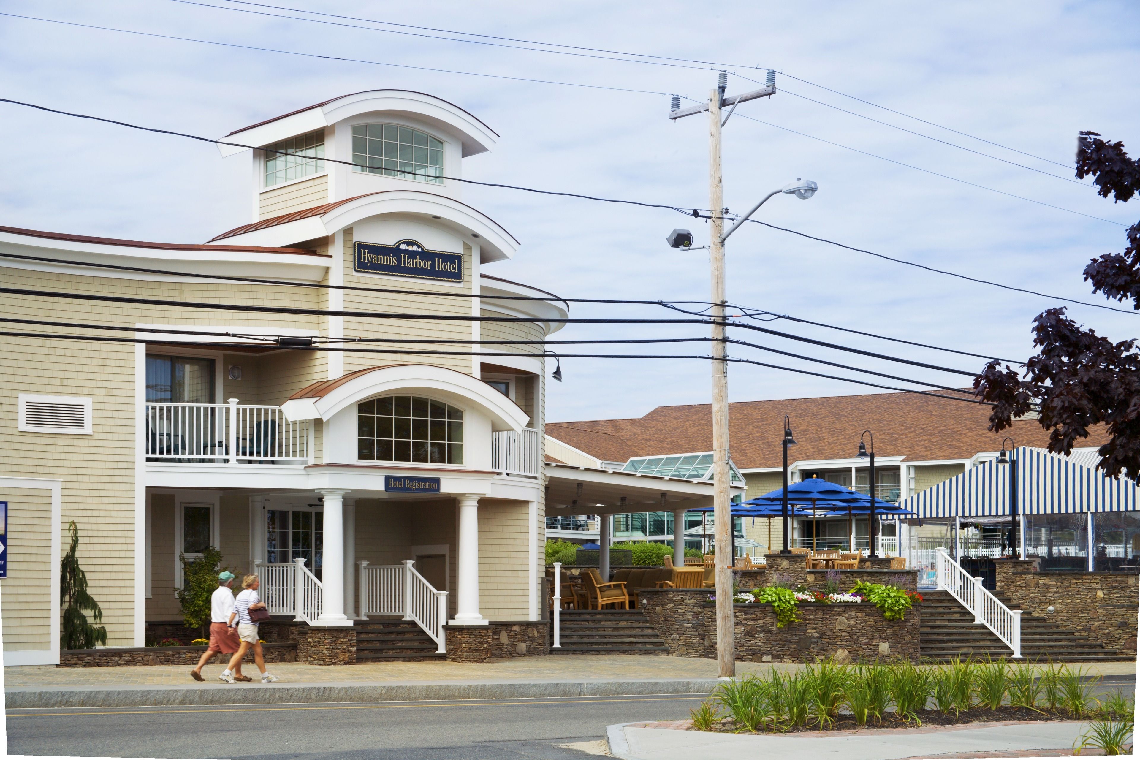 Een hotel met een balkon, een bord waarop 'Hyannis Harbor Hotel' staat, en een overdekt terras.