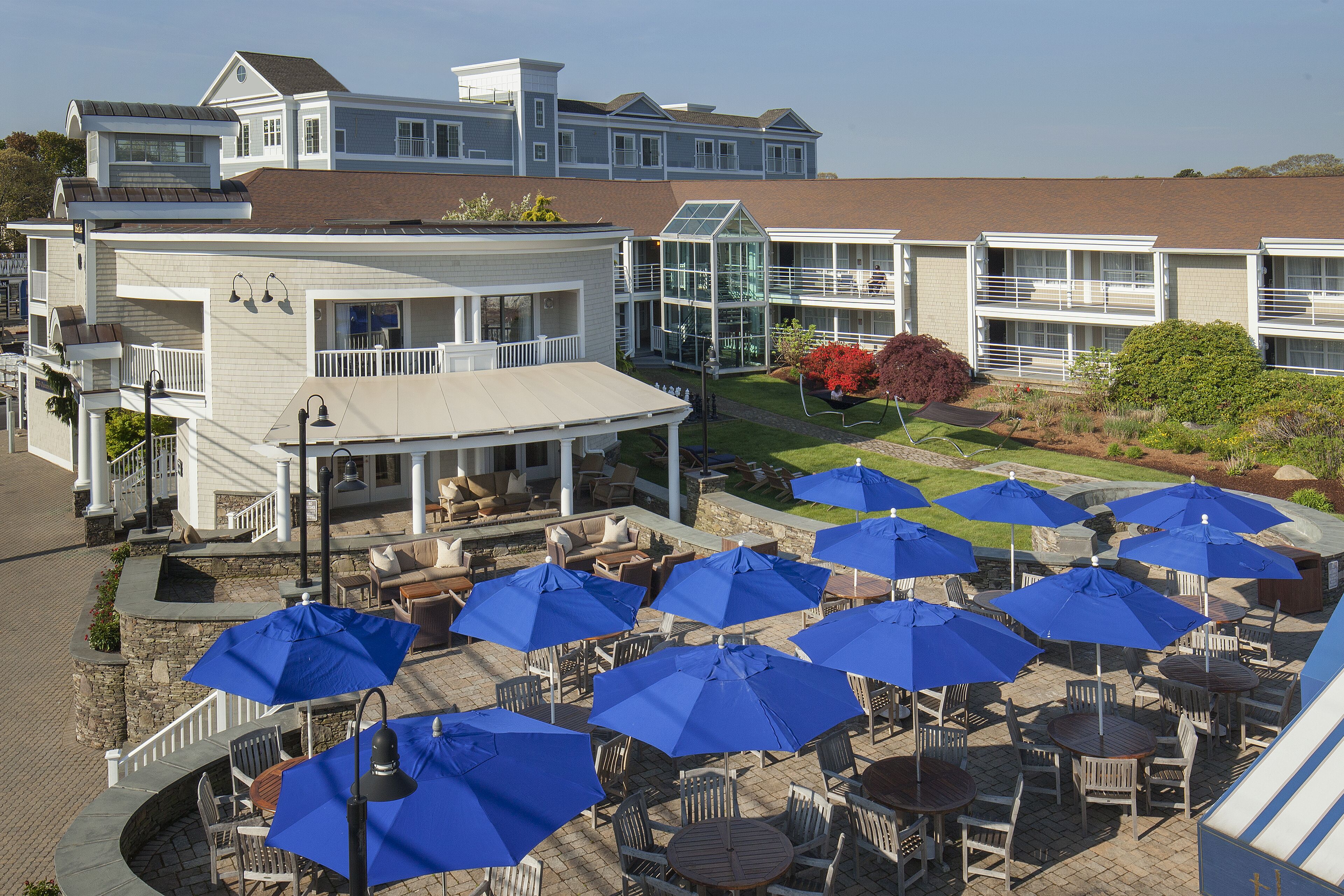 A hotel with outdoor seating and blue umbrellas.