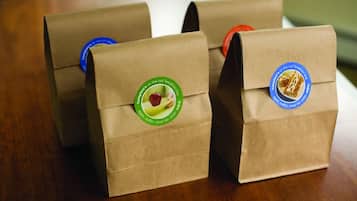 Three brown paper bags with logos and text on them.