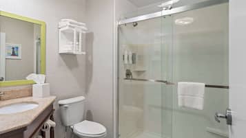 A modern bathroom with a glass-enclosed shower, a toilet, and a sink with a mirror.