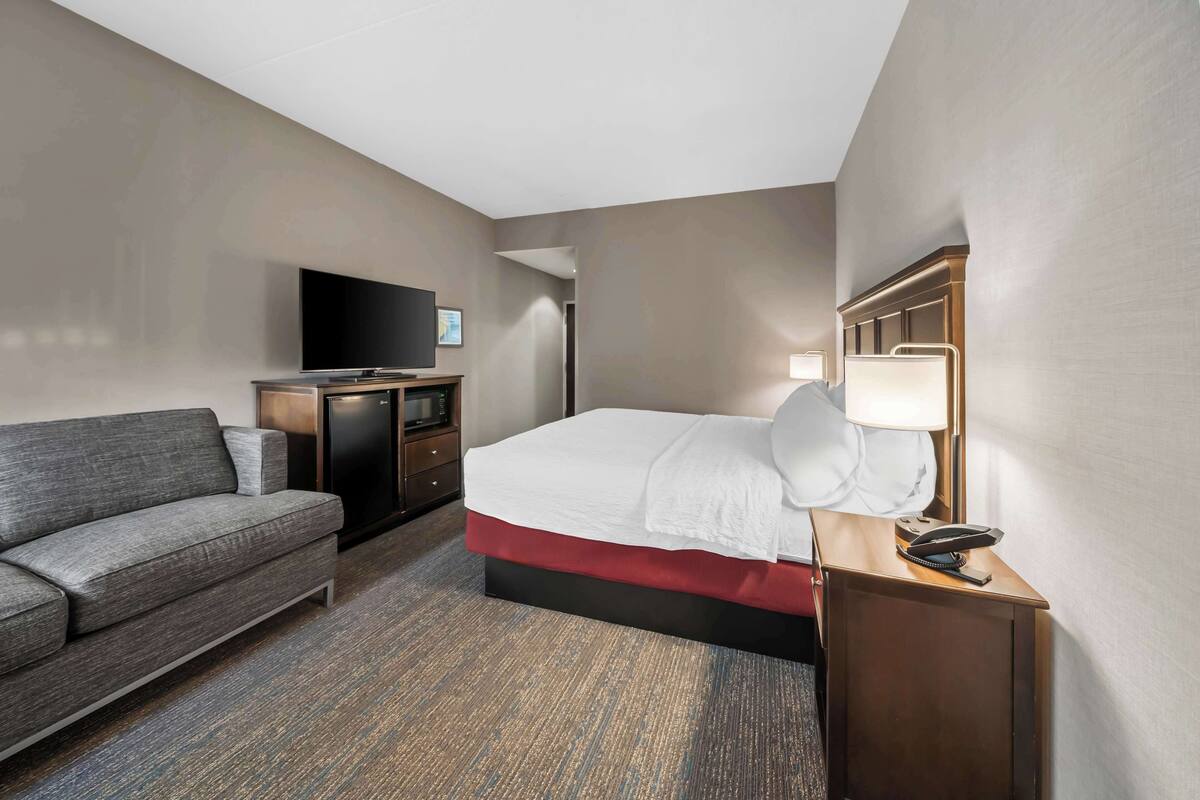A hotel room with a bed, a TV, a desk, and a couch.