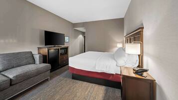 Ein Hotelzimmer mit Bett, Fernseher, Schreibtisch und einer Couch.