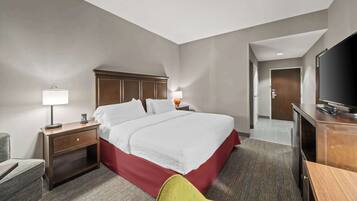 A hotel room with a large bed, a desk, a television, and a chair.