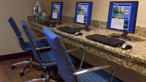 A reception desk with three computer monitors, a keyboard, and two blue office chairs. - Hampton Inn by Hilton New Bedford/Fairhaven (Fairhaven)