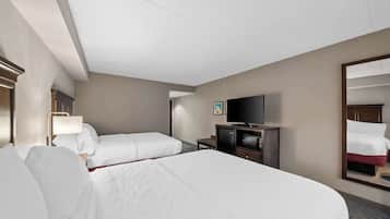 Quarto de hotel com duas camas, televisão, escrivaninha e espelho.