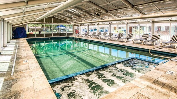 A covered swimming pool with lounge chairs and a lifeguard chair. - Cape Winds Resort (Hyannis)