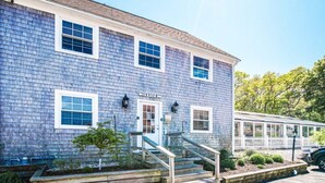 A two-story building with a sign reading "Coffee" above the entrance, wooden steps leading up to the door, and a small tree in front. - Cape Winds Resort (Hyannis)