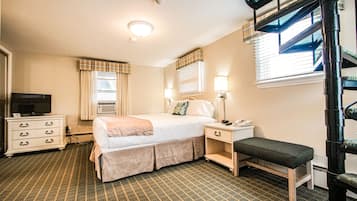 A hotel room with a bed, bedside table, lamp, chair, dresser, and a TV.