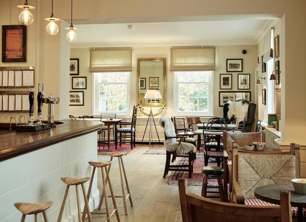 A spacious kitchen with a bar area, wooden chairs, and a dining table.