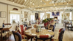 A spacious dining area with high ceilings, exposed beams, and hanging light fixtures. - The Goodwood Hotel (Chichester)
