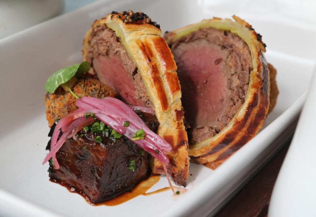 Prato de Wellington de carne com crosta dourada, servido em um prato branco.