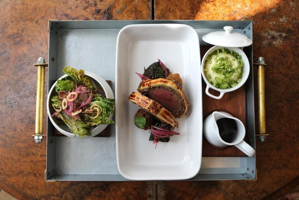 A tray with a salad, a steak, and a bowl of soup.