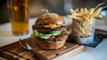 A burger with fries and a beer on a wooden board.