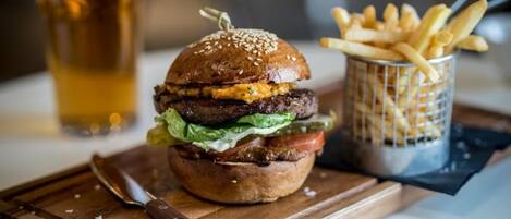 Una hamburguesa amb patates i una cervesa sobre una taula de fusta.