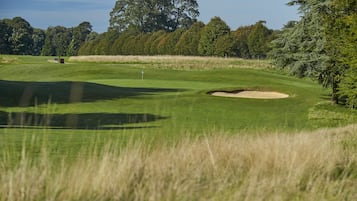 Campo de golf con un búnker de arena, una bandera y una vara de señales.