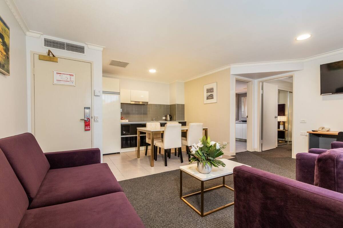 A modern living room with a sofa, a coffee table, and a dining area with chairs and a table.